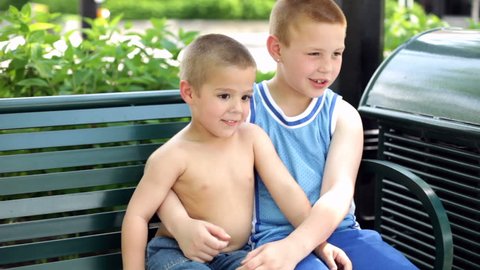 Two cute Boys sitting on park bench 