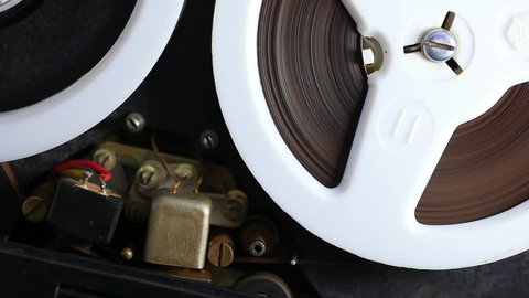Open reel audio tape recorder reels spinning. Close-up.