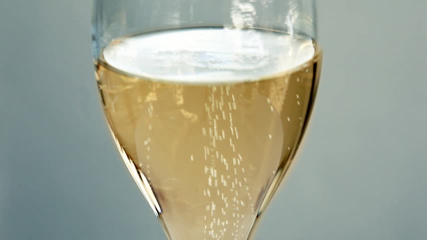 Close up of shiny golden champagne sparkling in glass with light effects and