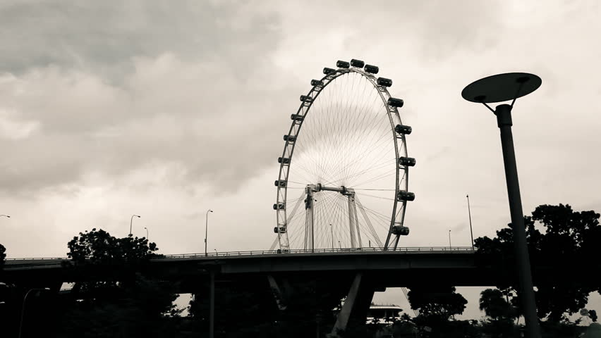 High contrast time lapse of Singapore ferris wheel with bridge and passing cars