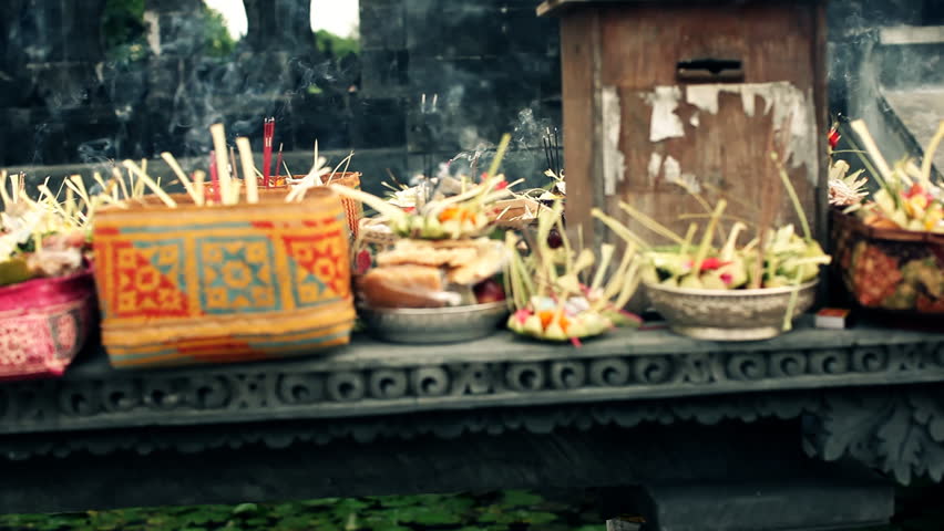 Steady cam pan over handmade sacrifices from plants and fruits with lit incense