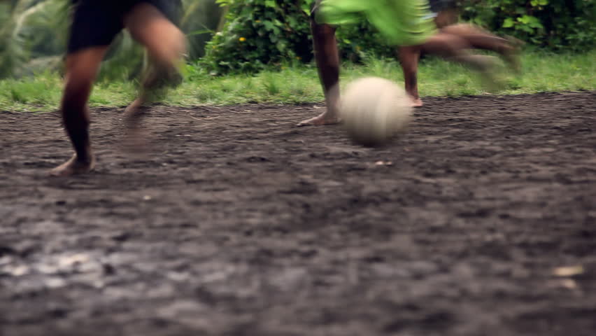 A gang of bar feet kids playing soccer on a muddy field. Serial of slow motion