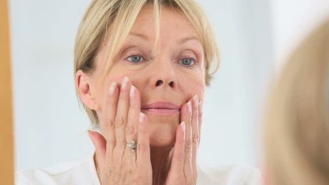 Senior woman applying cosmetic lotion on her face