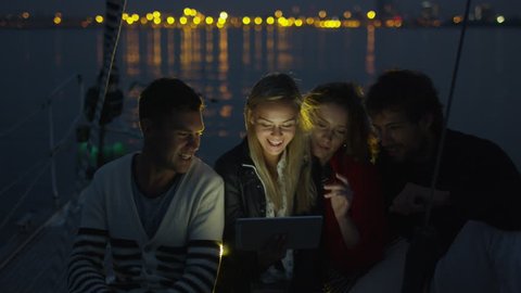 Group of people are using tablet on a yacht in the sea at night. Shot on RED Cinema Camera in 4K (UHD).