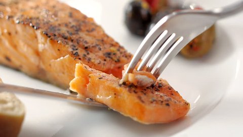 pick up grilled salmon from dish with olives and Baguette