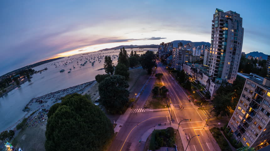 Time lapse fisheye view of English Bay in downtown Vancouver from sunset to fireworks event and afterwards with people and boats leaving