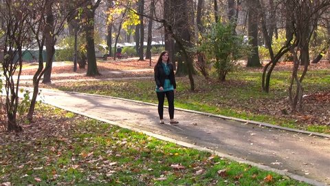 Girl goes autumn park/happy girl in autumn park walking path goes along