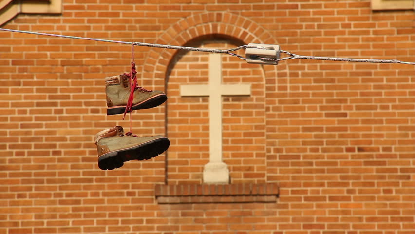 Boots hang on a power line in front of a church.