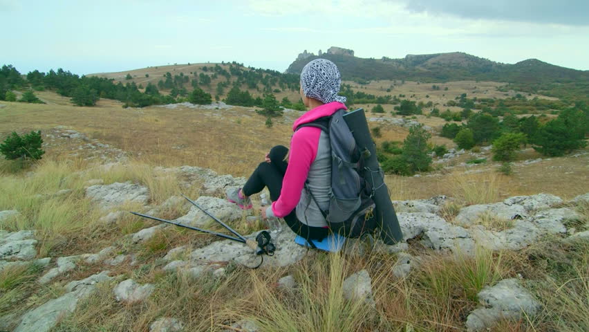 JIB CRANE: Woman hiker hiking mountain highlands relaxing on edge of cliff rear view, Ai-Petri plateau, Crimea