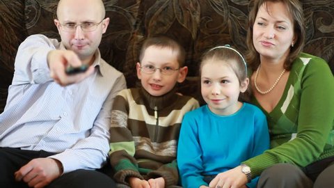 family members sitting on couch and pass each other broken remote control