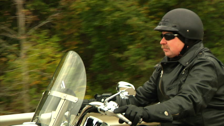 A biker rides his motorcycle on a Fall afternoon.