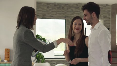 Real estate agent giving keys of new home to happy couple
