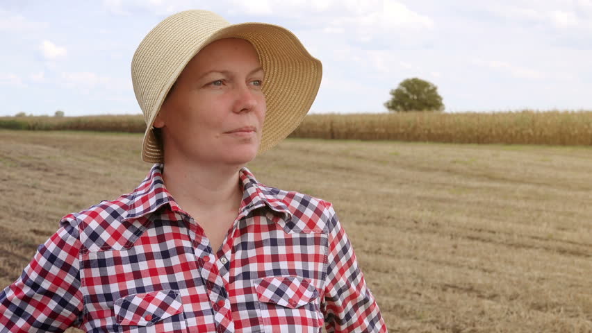 Concerned farmer planning new seeding season, female farmer with straw hat at cultivated field