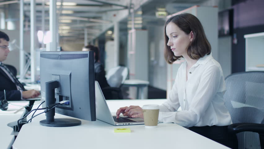 Female Office Worker is Working on Laptop and Drinking Coffee. Shot on RED Cinema Camera in 4K (UHD). | Shutterstock HD Video #11956736