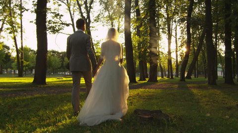 Happy young newlyweds are walking in a park. Shot on RED Cinema Camera in 4K (UHD). Video de stock