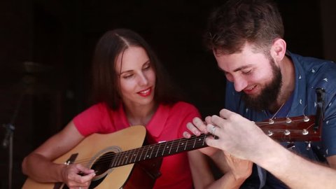 man teaching woman to play guitar