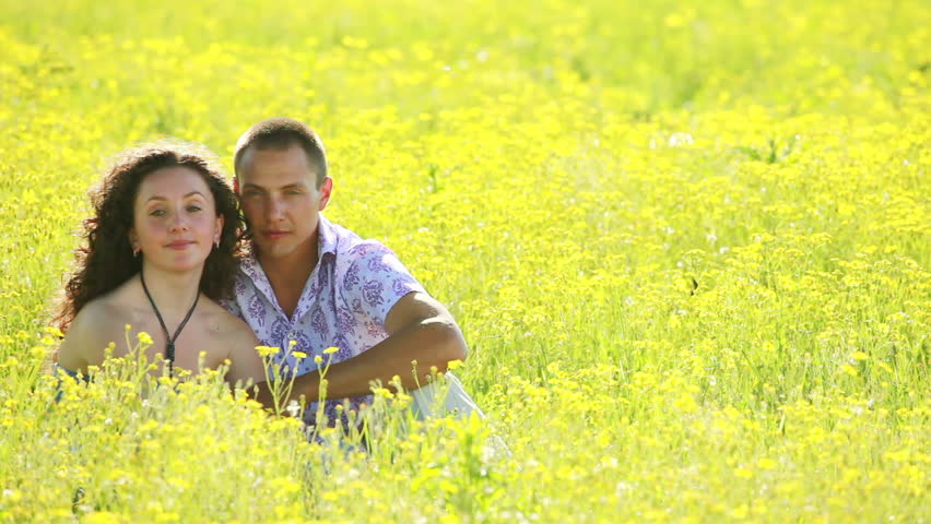 Young love couple sitting in a meadow. Tripod static. 