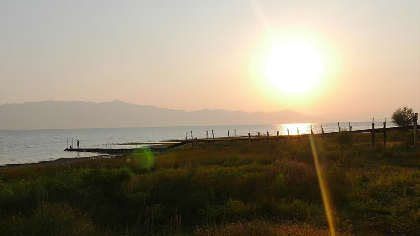 TIME-LAPS OF SUNSET AT SKODER LAKE, ALBANIA AND PEOPLES MOVING ON A  SHORE