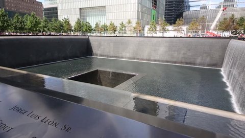 NYC - SEP 8, 2014: Square waterfall memorial of people killed in terrorist attacks on September 11, 2001 and skyscrapers