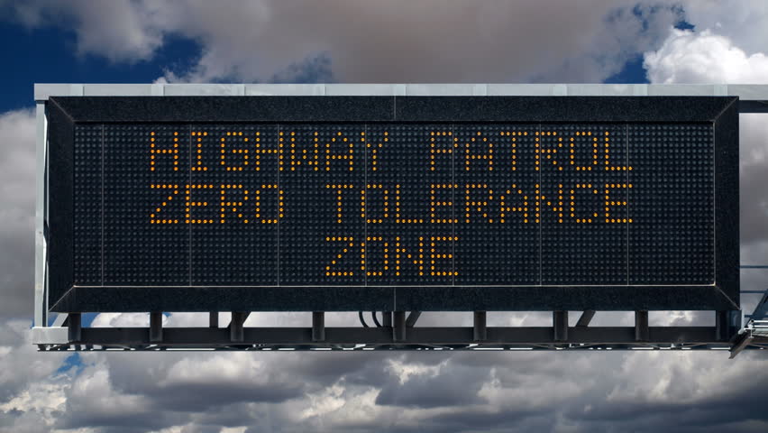 Zero tolerance highway patrol overhead freeway warning sign with time lapse clouds.