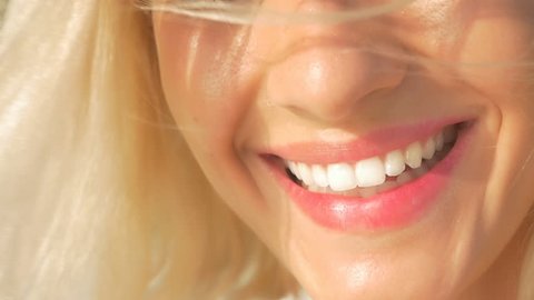 SLOW MOTION CLOSE UP: Beautiful young woman with perfect white teeth starts laughing