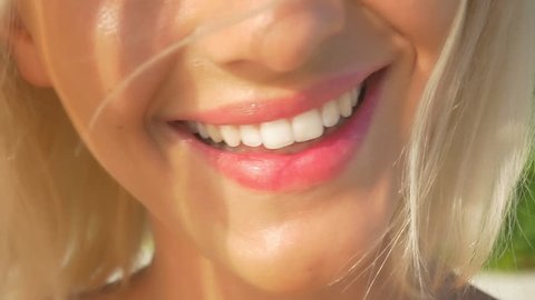 SLOW MOTION CLOSE UP: Beautiful blonde girl smiling, showing her perfect white teeth