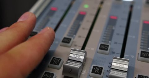 Close up shot of an audio mixer and a man pulling up the knobs, the shot is moving from left to right...