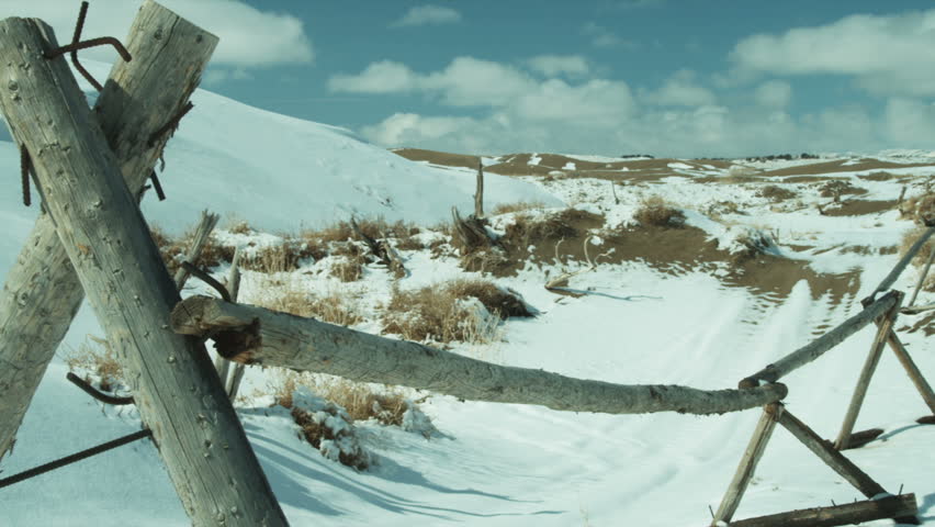 Close-up pan of a homemade fence in the snowy countryside.