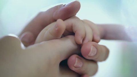 Concept of love and family. hands of mother and baby closeup, Hand in hand. Mother care. Caring mother with baby, Playing with baby. Slow Motion.