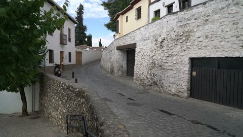 Granada, Andalusia, Spain - Sept 29, 2015. Single motorcycle driving through a typical cobblestone street in the Albayzin district, or old Moorish quarter.
