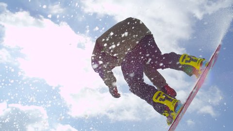 SLOW MOTION CLOSE UP: Extreme snowboarder jumping big air kicker in sunny winter in mountain snow park : vidéo de stock