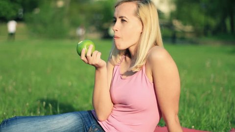 Attractive happy woman biting fresh apple outdoor
