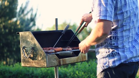 Man cooking meat on the barbecue grill, outdoors, camera stabilizer shot
