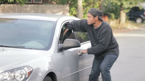 Crime concept, criminal thief stealing bag from parked car