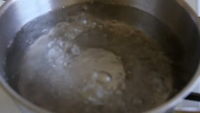 Boiling water in a kitchen pot as a symbol of cooking or food preparation and sterilization of contaminated tap water for healthy pure drinking liquid.
