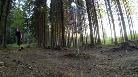 Disc golf players putting at a basket surrounded by forest in Finland.: stockvideo