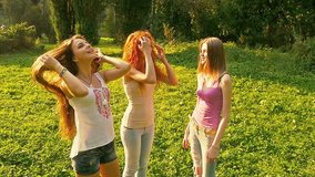 Three friends, young pretty girls, caucasians, having fun outdoors in nature, walking, dancing, laughing, fooling around, slow motion.
