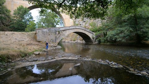 PIERRE-PERTHUIS, FRANCE - 30th JULY 2015: Tourists and old stone bridge over river La Cure in the Pierre-Perthuis, Burgundy, France, Europe