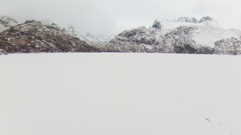 Drone flying above frozen lake covered in snow