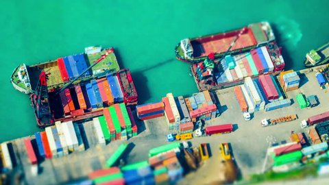 HONG KONG - JAN 23, 2015: Cargo ships loaded by crane with cargo containers at a busy port terminal. Hong Kong. Tilt Shift effect. Time lapse form aerial view point
