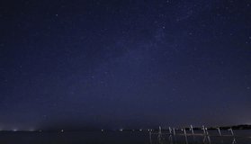 Stars rotating in a whirling mass of vortex moving over cottage pier on lake in summer.