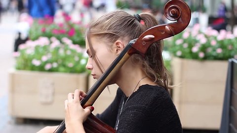 Beautiful slender girl playing the cello on a street