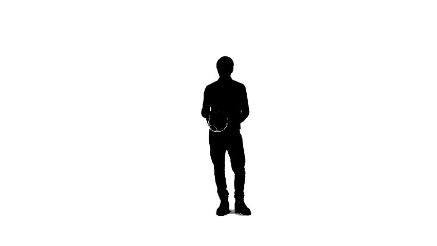 Silhouette of a man with a ball which trains. The athlete throws the ball up and throws the ball on the floor around himself and catches with his hands. Snippet filmed in the Studio on a white