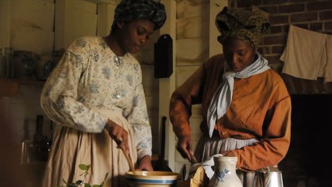 NORTH CAROLINA - SPRING 2015 - Reenactment. Enslaved african-americans, slavery and black slaves working at farm, cooking, building fire, talking circa 1830s - 1860s era. Civil War farmstead.