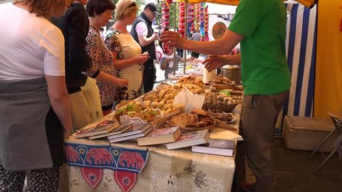VILNIUS, LITHUANIA - JUNE 20, 2015: Eco bakery store products and customer people buy sweets and mealy products with meat in outdoors fair on June 20, 2015 in Vilnius, Lithuania. Zoom out shot. 4K