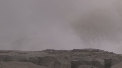 Huge powerful waves breaking at seawall in major severe storm.
