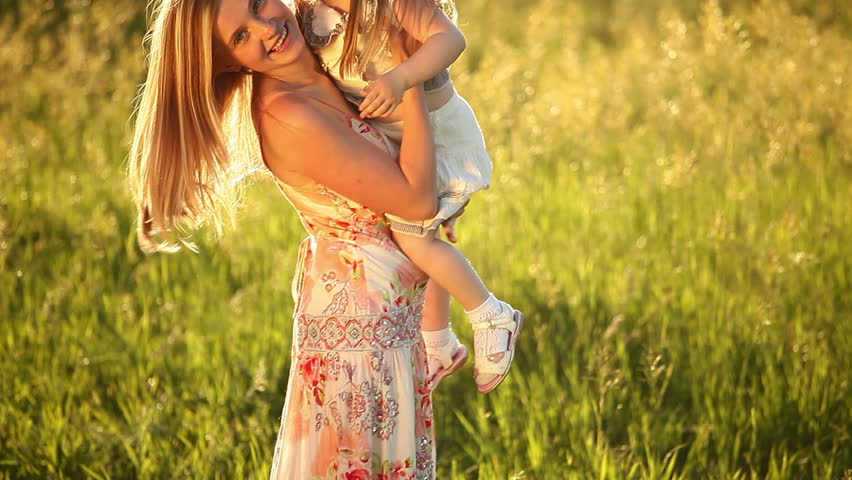 Happy mother playing with baby on the meadow 