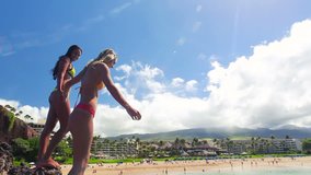 Two Girl Friends Jump Off Cliff H into Ocean in Bikinis in Hawaii. Summer Outdoor Lifestyle.