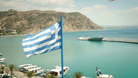 Greek flag waving in the wind with a beautiful view on the coastline of Greece . Shoot on Digital Cinema Camera in hd.