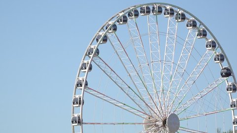 Ferris wheel rotates on blue sky background 4k